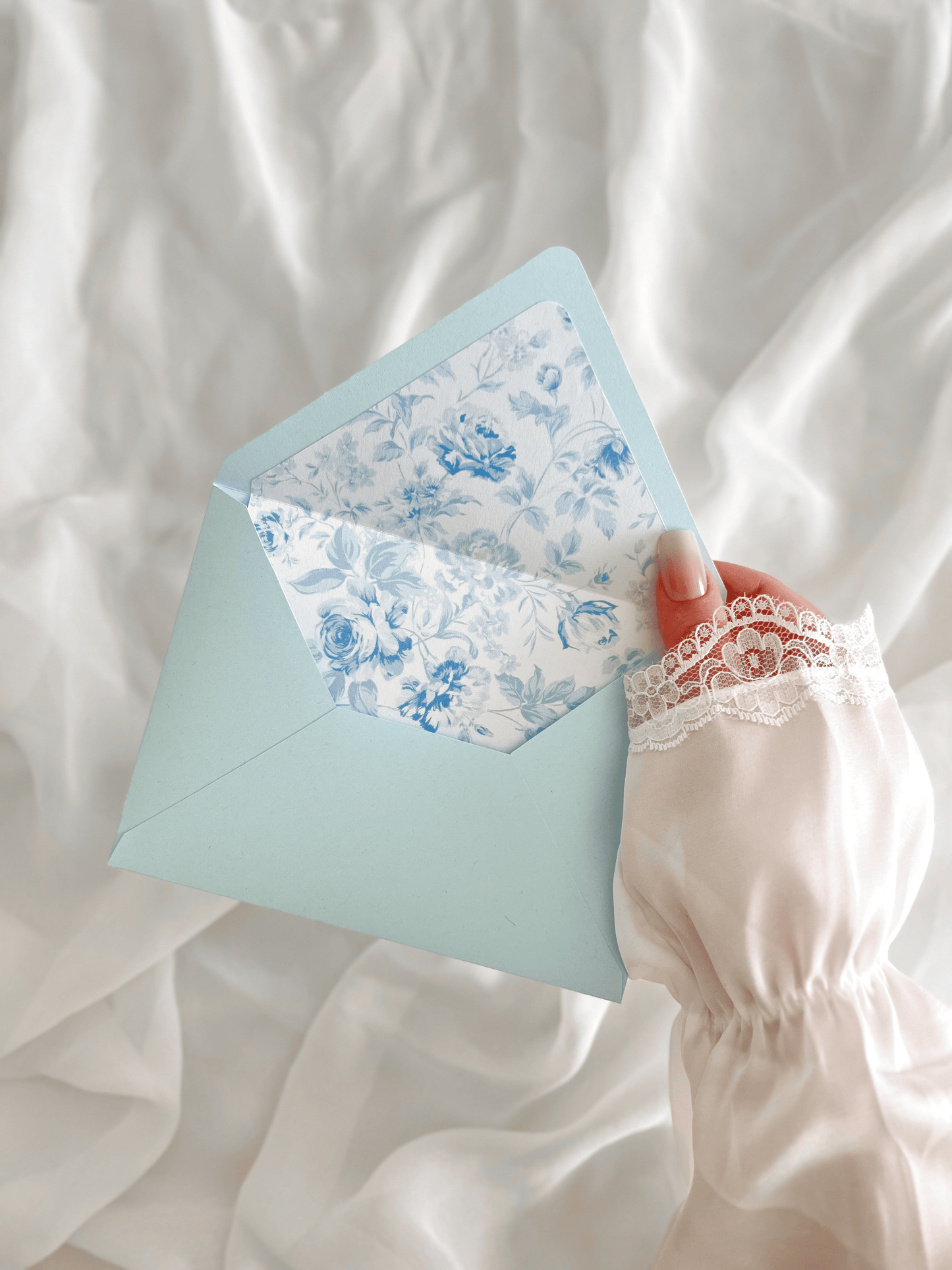 Faire-part de mariage personnalisé Collection LEA avec enveloppe bleu clair, liner floral bleu et blanc, découpe antique, ruban en mousseline de soie et carte RSVP assortie.