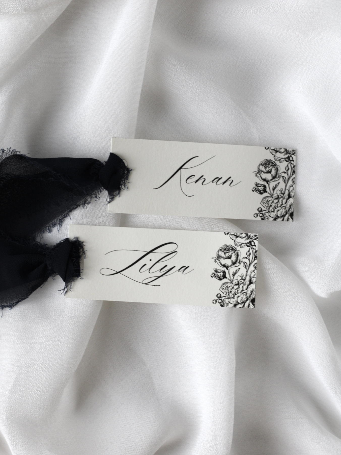 Marque-place de mariage personnalisé Collection CAMELIA au format 10 × 4 cm avec délicat motif de fleurs de camélia, disponible avec ou sans ruban ou gland.