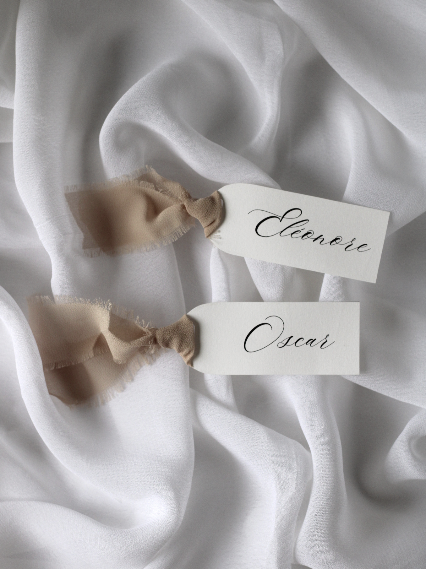 Marque-place de mariage personnalisé Collection NACRE au format 10 × 4 cm avec élégante découpe en forme d'arche, disponible avec ou sans ruban ou gland.