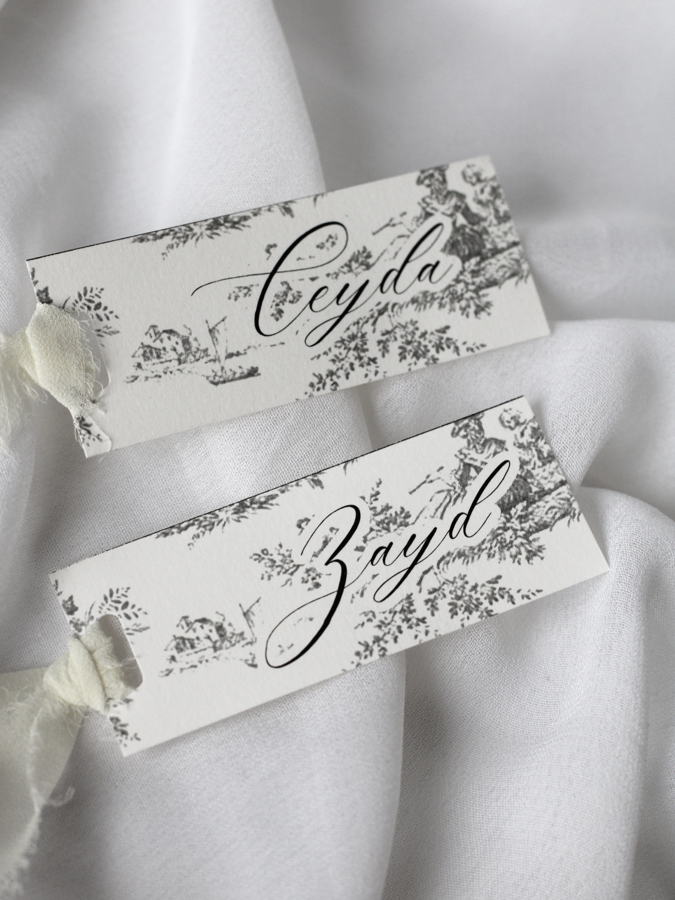 Marque-place de mariage personnalisé Collection VERSAILLES au format 10 × 4 cm avec élégant motif inspiré de la Toile de Jouy, disponible avec ou sans ruban ou gland.