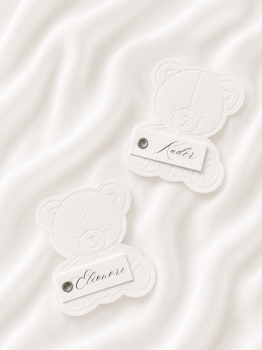 Marque-place personnalisé en forme d'ourson avec découpe Die-Cut, prénom embossé et œillet décoratif.