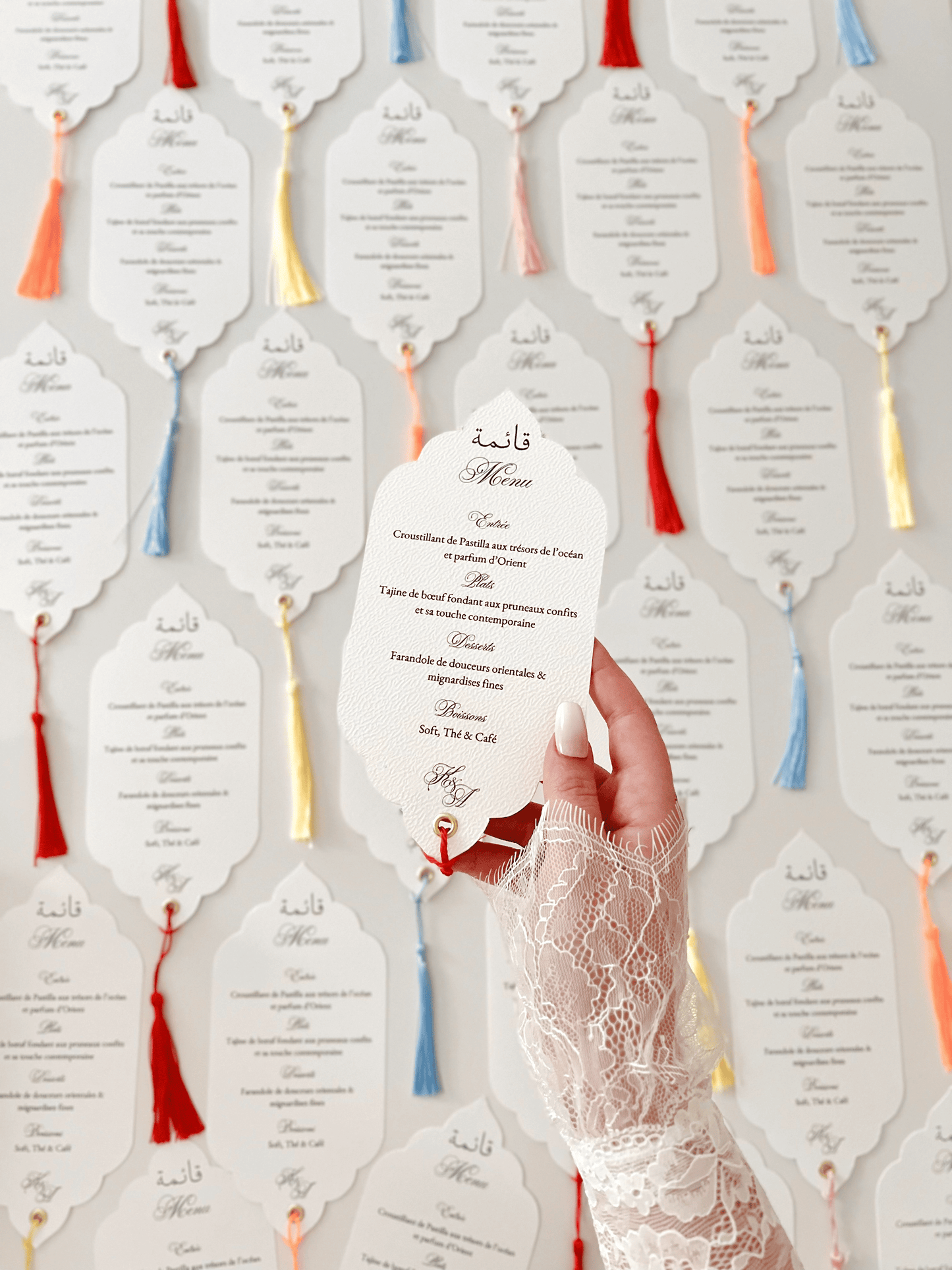 Menu de mariage personnalisé Collection ORIENT avec découpe Die Cut, calligraphie arabe bilingue, monogramme et finition avec gland coloré.
