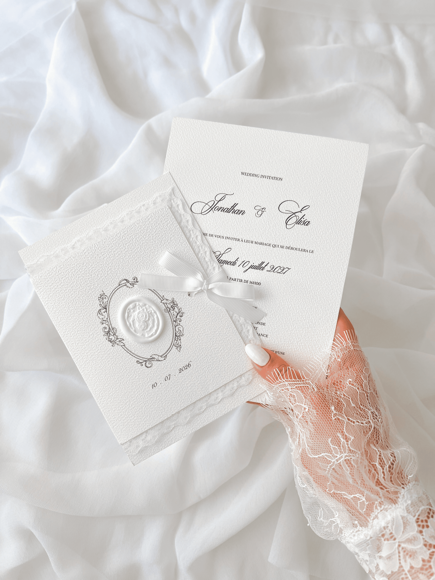 Faire-part de mariage personnalisé Collection ÉTERNELLE avec pochette blanche à contour dentelle, ruban personnalisé avec la date du mariage, monogramme et cachet de cire.