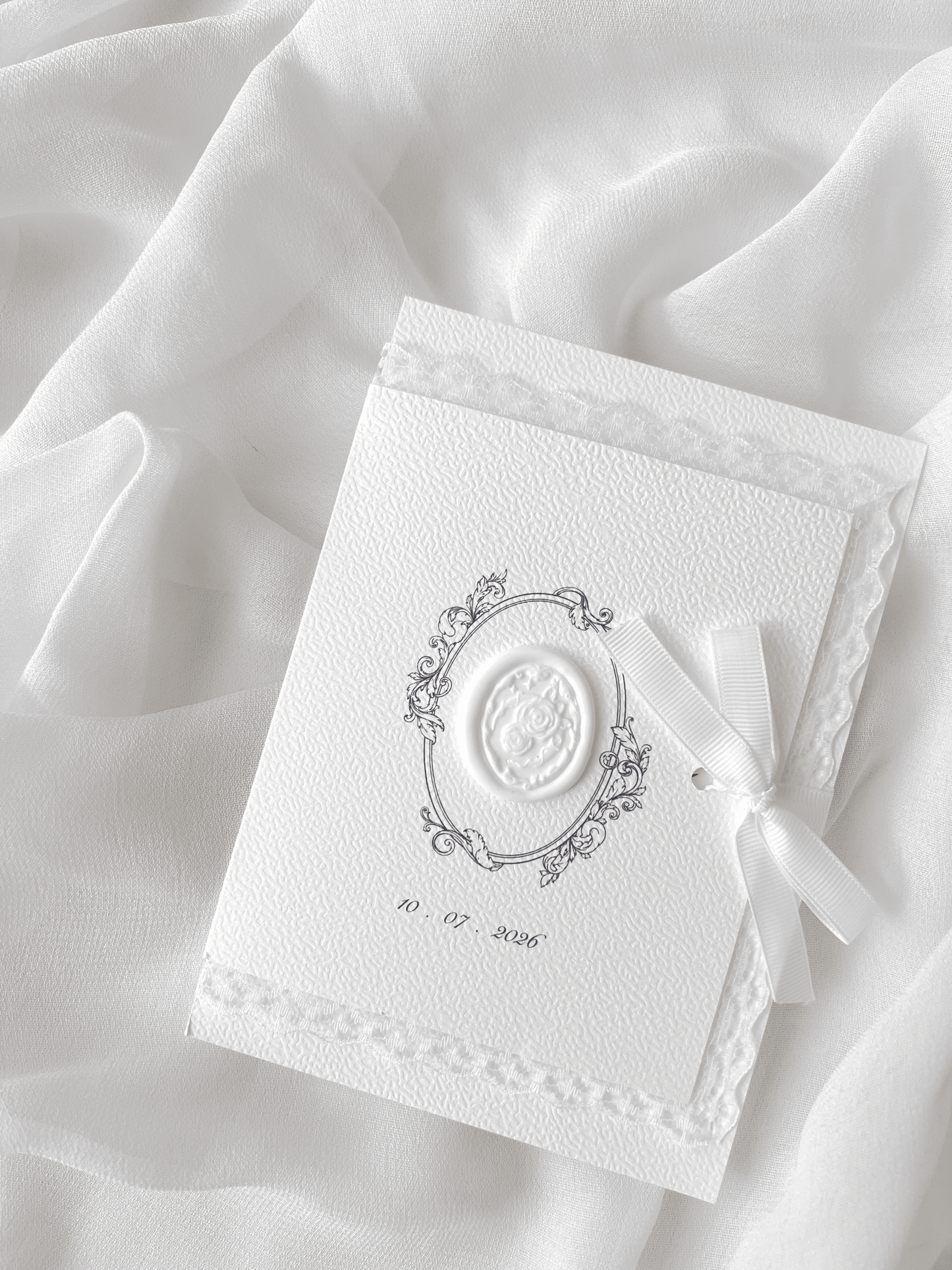 Faire-part de mariage personnalisé Collection ÉTERNELLE avec pochette blanche à contour dentelle, ruban personnalisé avec la date du mariage, monogramme et cachet de cire.