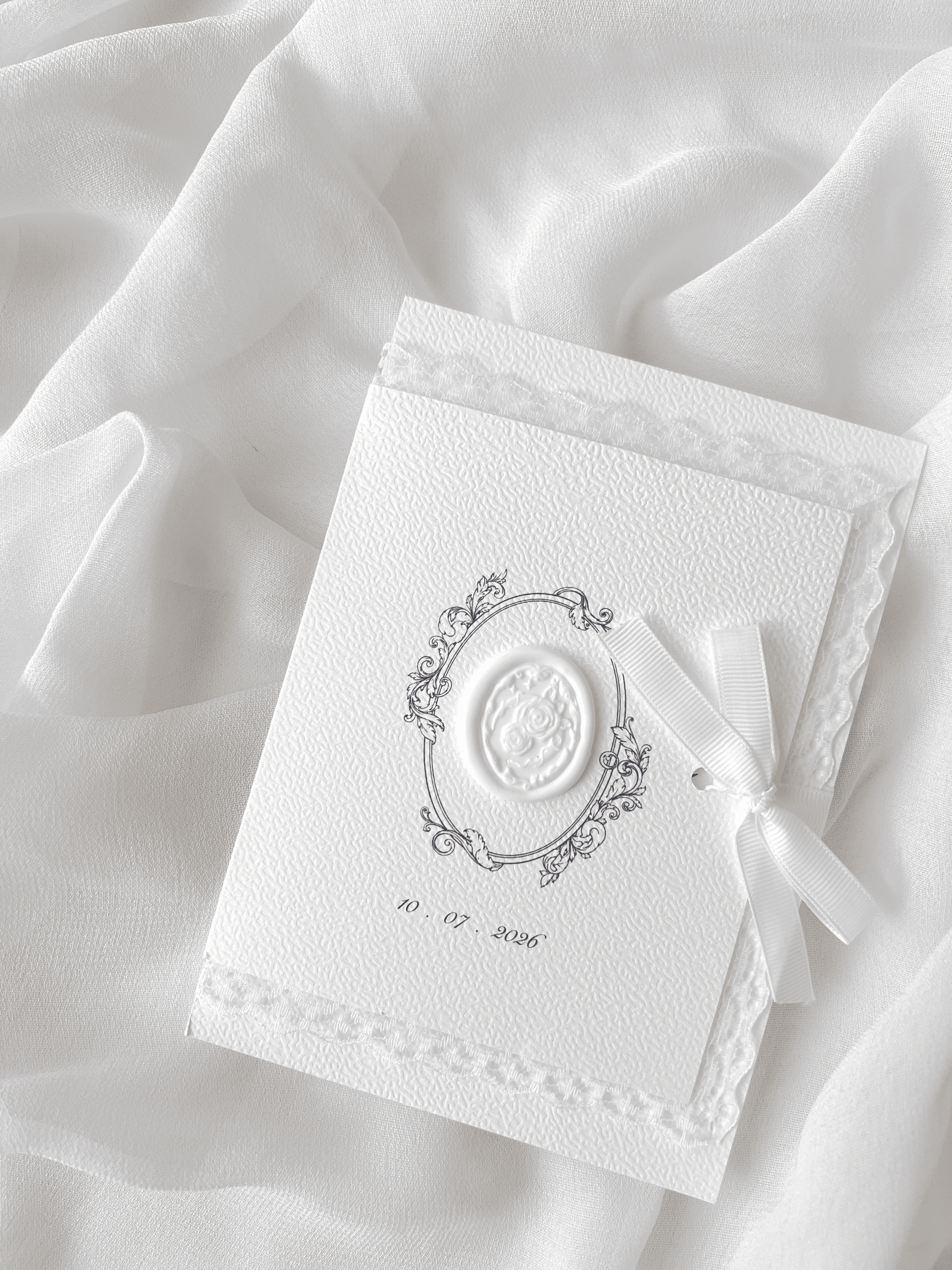 Faire-part de mariage personnalisé Collection ÉTERNELLE avec pochette blanche à contour dentelle, ruban personnalisé avec la date du mariage, monogramme et cachet de cire.