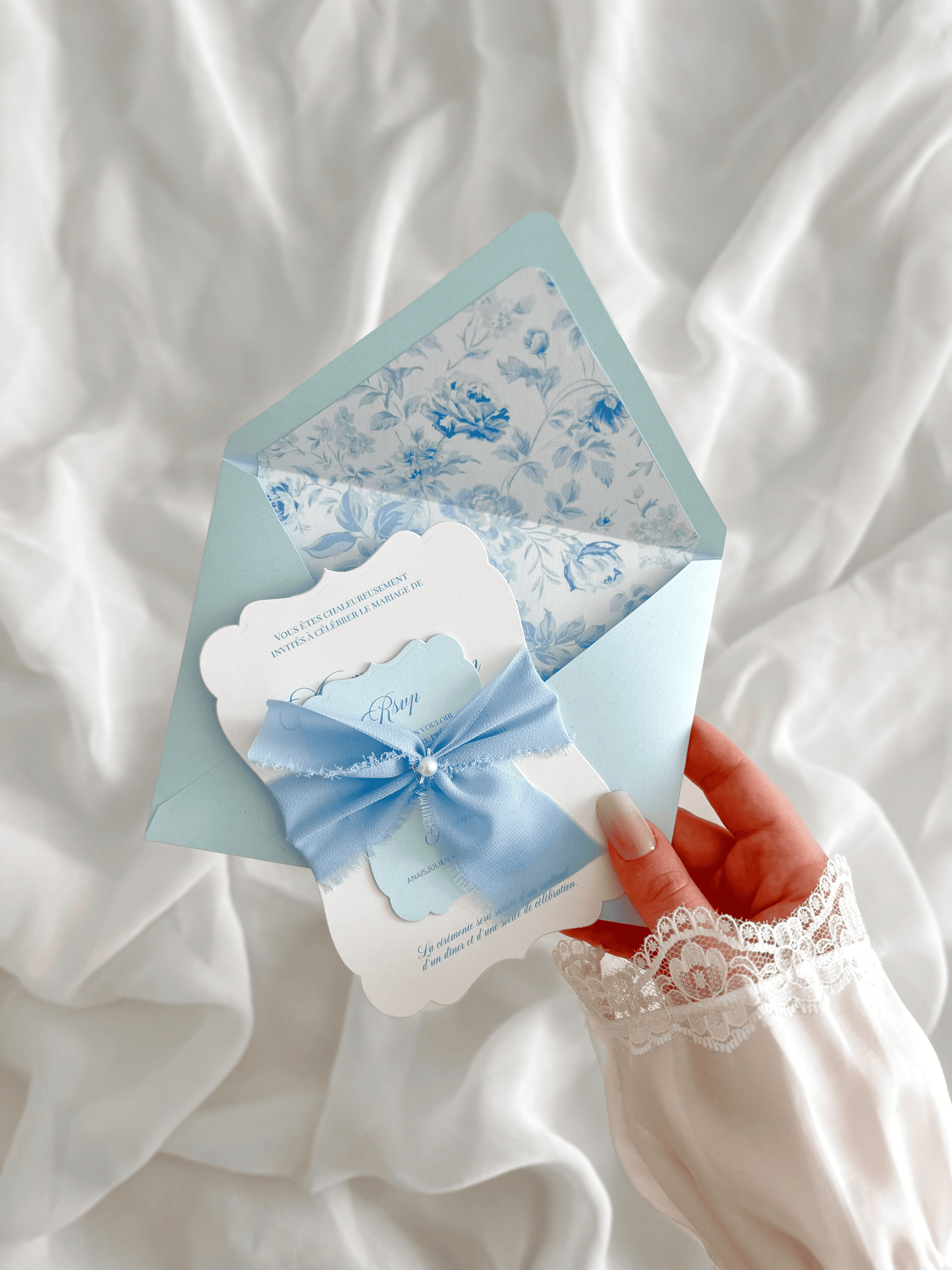 Faire-part de mariage personnalisé Collection LEA avec enveloppe bleu clair, liner floral bleu et blanc, découpe antique, ruban en mousseline de soie et carte RSVP assortie.