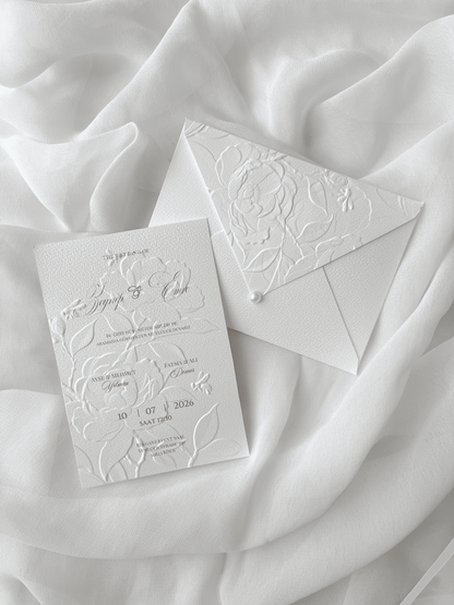 Faire-part de mariage personnalisé Collection PEONY avec enveloppe blanche embossée de motifs pivoines, invitation assortie avec embossage floral, perle décorative et carte RSVP en option.