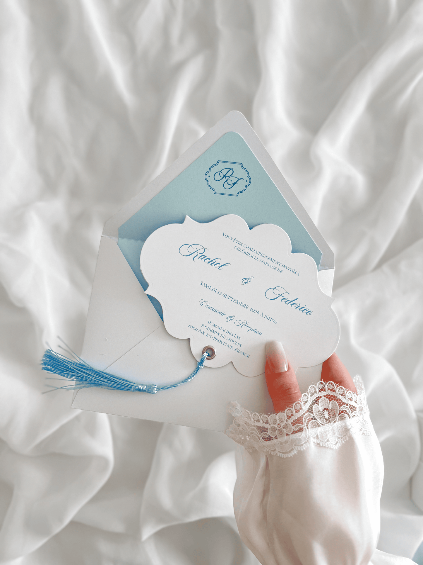 Faire-part de mariage personnalisé Collection RACHEL avec enveloppe blanche, liner bleu clair personnalisé avec monogramme, découpe impériale, gland bleu et carte RSVP assortie.