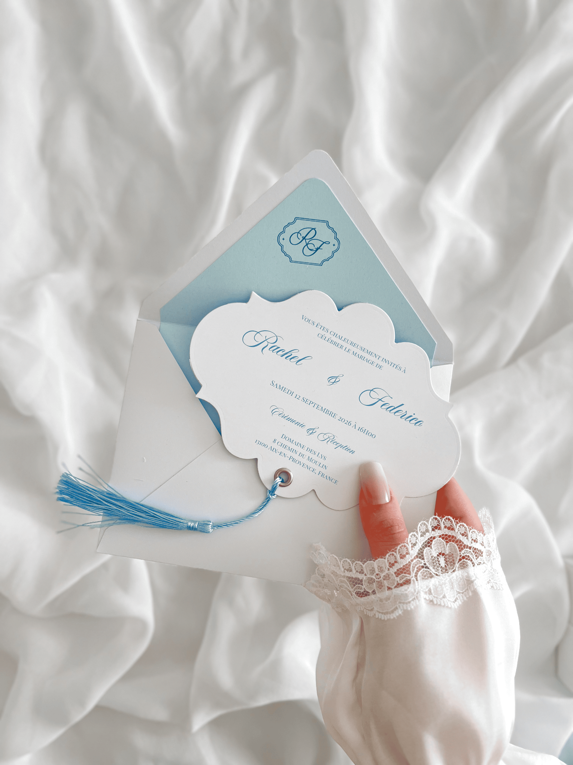 Faire-part de mariage personnalisé Collection RACHEL avec enveloppe blanche, liner bleu clair personnalisé avec monogramme, découpe impériale, gland bleu et carte RSVP assortie.