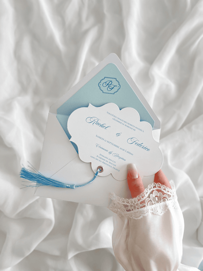 Faire-part de mariage personnalisé Collection RACHEL avec enveloppe blanche, liner bleu clair personnalisé avec monogramme, découpe impériale, gland bleu et carte RSVP assortie.
