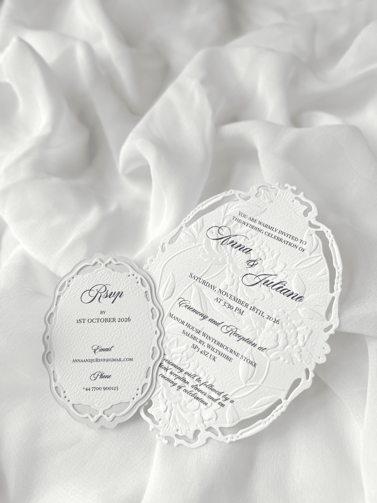 Faire-part de mariage personnalisé Collection WINDSOR avec enveloppe grège embossée, invitation ovale ajourée, ruban en organza, perle décorative et carte RSVP avec monogramme.
