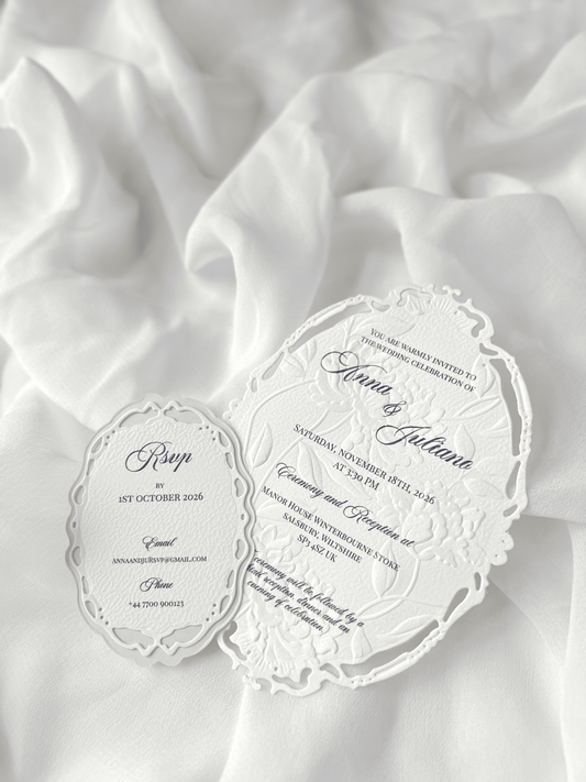 Faire-part de mariage personnalisé Collection WINDSOR avec enveloppe grège embossée, invitation ovale ajourée, ruban en organza, perle décorative et carte RSVP avec monogramme.