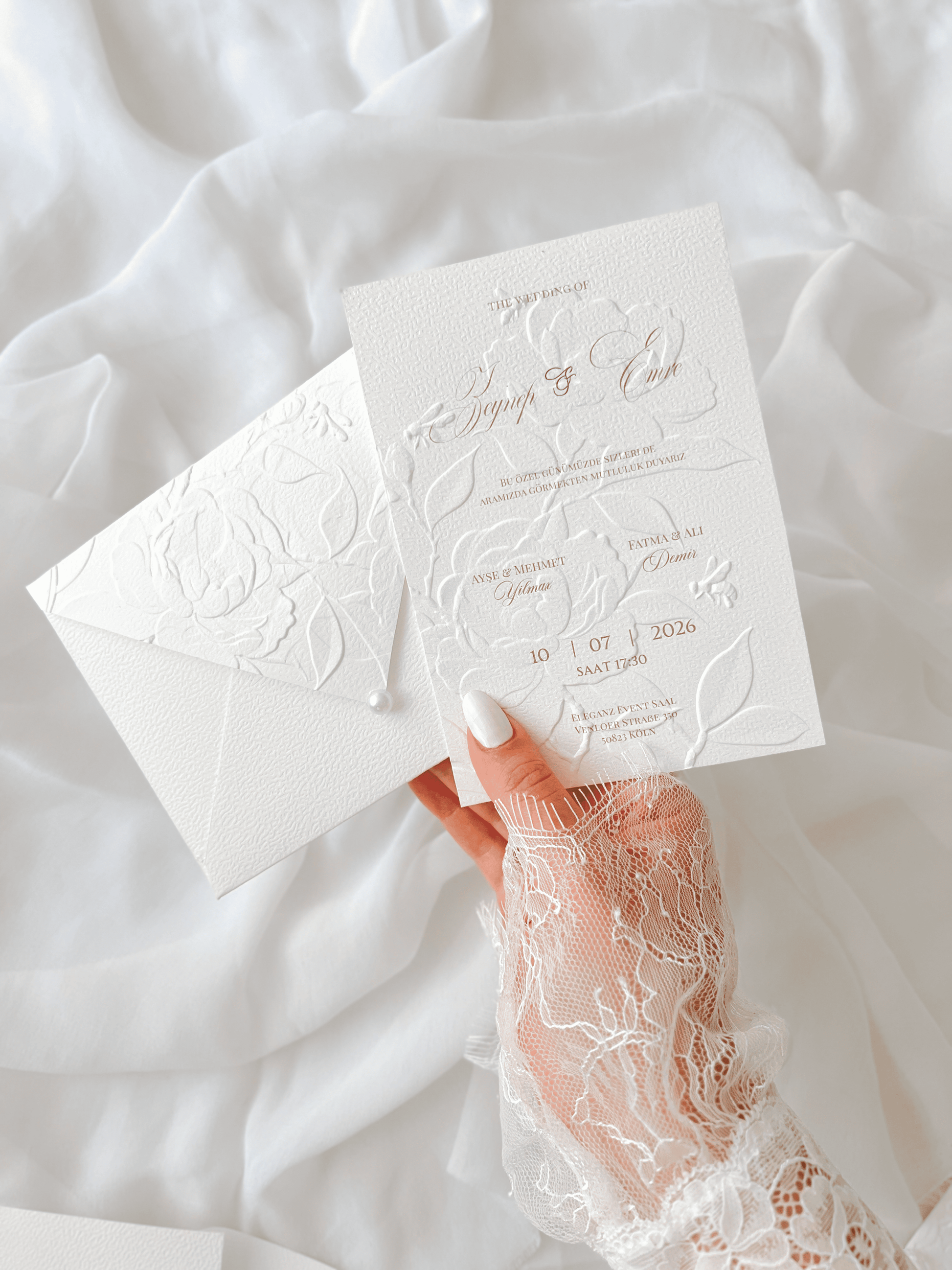 Faire-part de mariage personnalisé Collection PEONY avec enveloppe blanche embossée de motifs pivoines, invitation assortie avec embossage floral, perle décorative et carte RSVP en option.