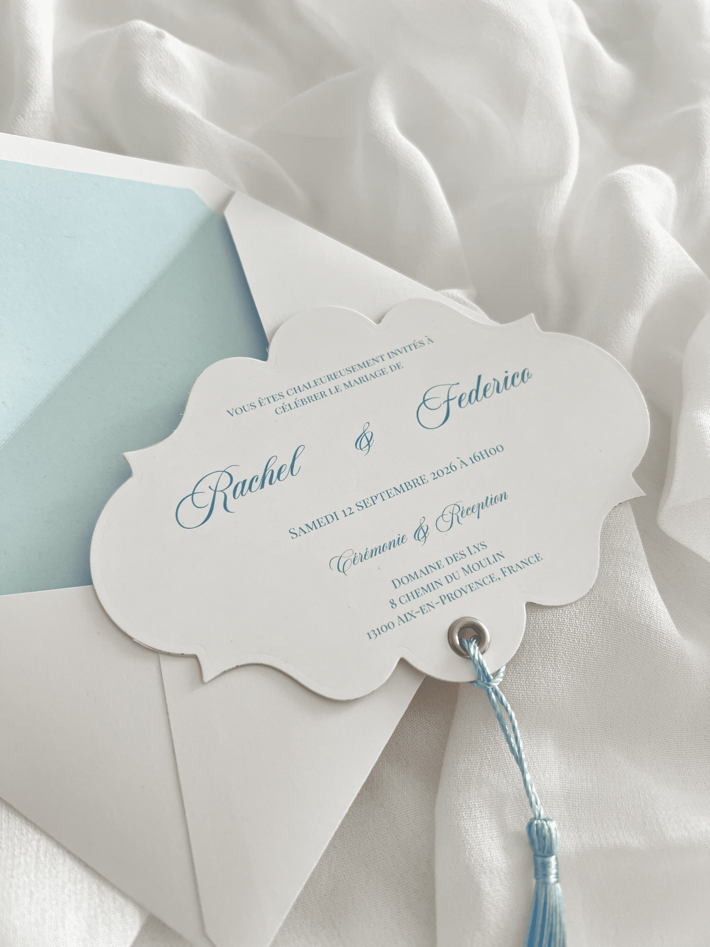 Faire-part de mariage personnalisé Collection RACHEL avec enveloppe blanche, liner bleu clair personnalisé avec monogramme, découpe impériale, gland bleu et carte RSVP assortie.