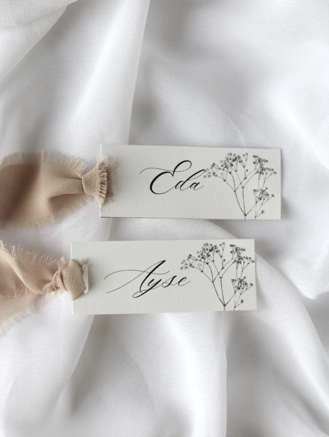 Marque-place de mariage personnalisé Collection DAPHNE au format 10 × 4 cm avec décoration en gypsophile, disponible avec ou sans ruban ou gland.
