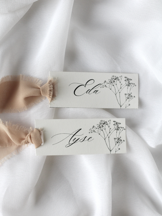 Marque-place de mariage personnalisé Collection DAPHNE au format 10 × 4 cm avec décoration en gypsophile, disponible avec ou sans ruban ou gland.