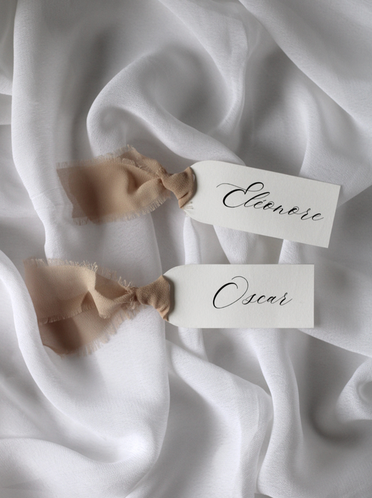 Marque-place de mariage personnalisé Collection NACRE au format 10 × 4 cm avec élégante découpe en forme d'arche, disponible avec ou sans ruban ou gland.
