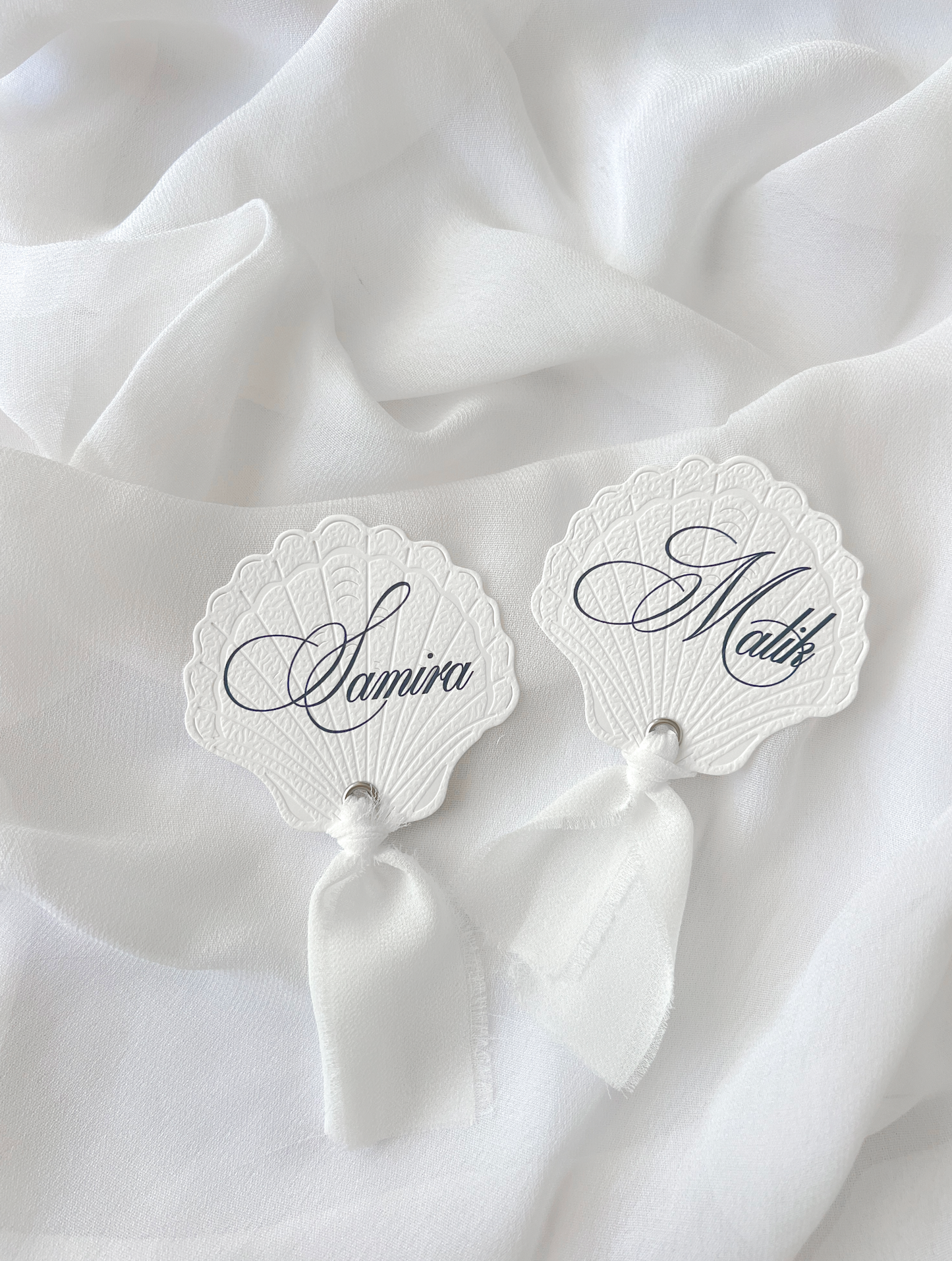 Marque-place de mariage personnalisé Collection SHELL I en forme de coquillage avec découpe Die-Cut et prénom imprimé, disponible avec ou sans ruban ou gland.
