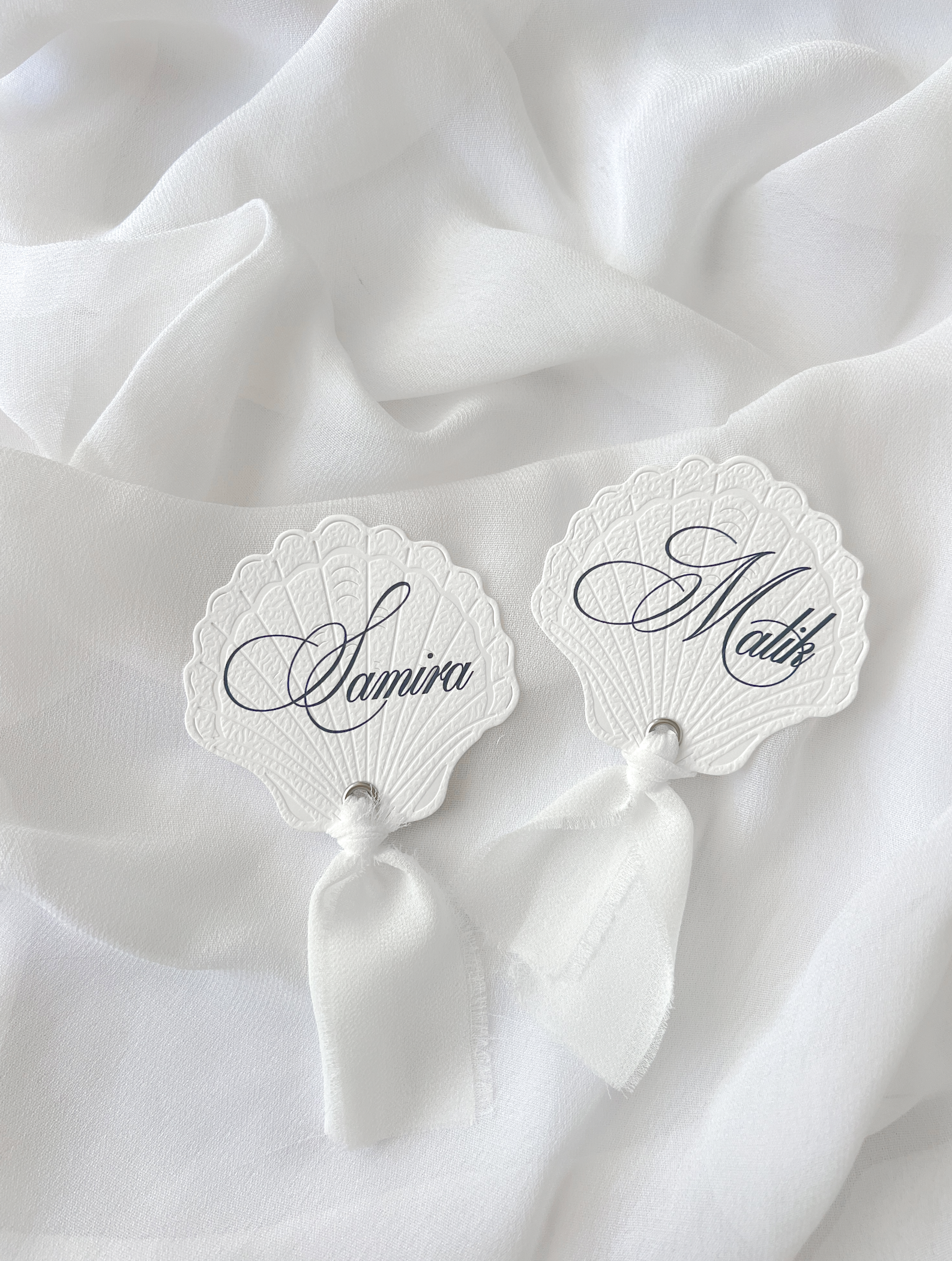 Marque-place de mariage personnalisé Collection SHELL I en forme de coquillage avec découpe Die-Cut et prénom imprimé, disponible avec ou sans ruban ou gland.