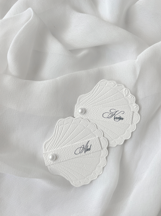 Marque-place de mariage personnalisé Collection SHELL II en forme de coquillage avec carte prénom personnalisée et finition perle décorative.