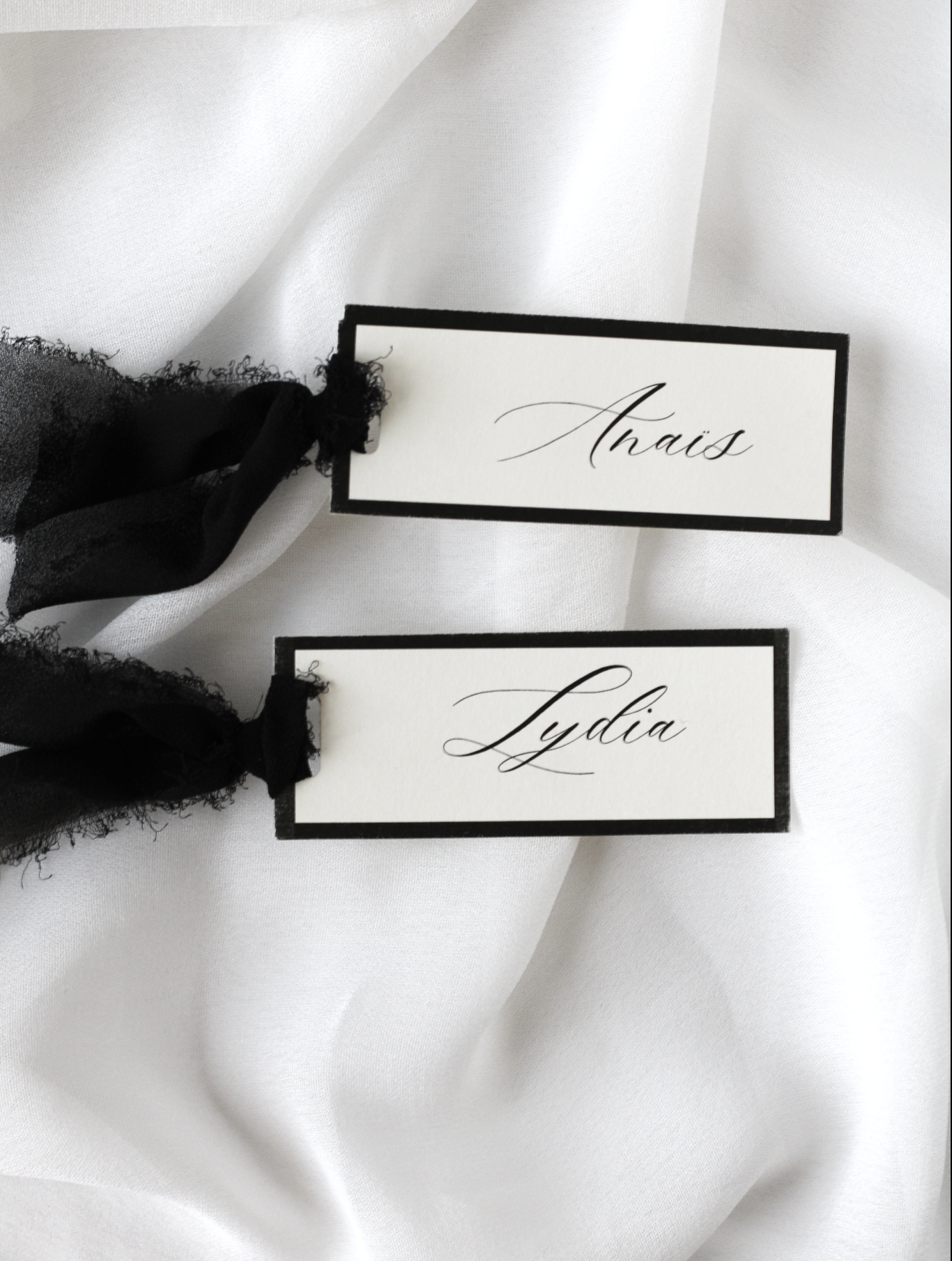 Marque-place de mariage personnalisé Collection SIGNATURE au format 10 × 4 cm avec élégante bordure noire, disponible avec ou sans ruban ou gland.