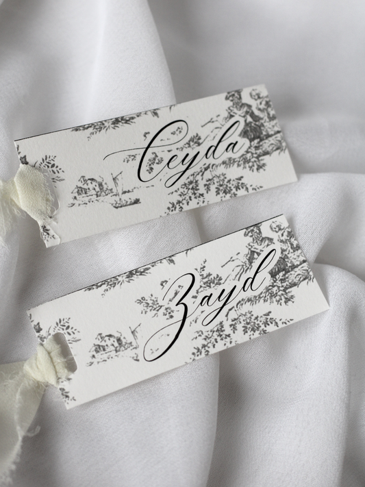 Marque-place de mariage personnalisé Collection VERSAILLES au format 10 × 4 cm avec élégant motif inspiré de la Toile de Jouy, disponible avec ou sans ruban ou gland.