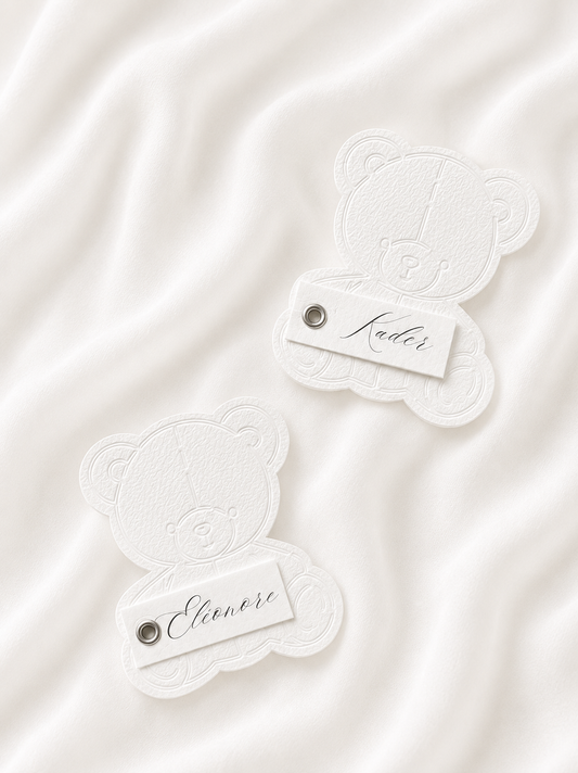 Marque-place personnalisé en forme d'ourson avec découpe Die-Cut, prénom embossé et œillet décoratif.