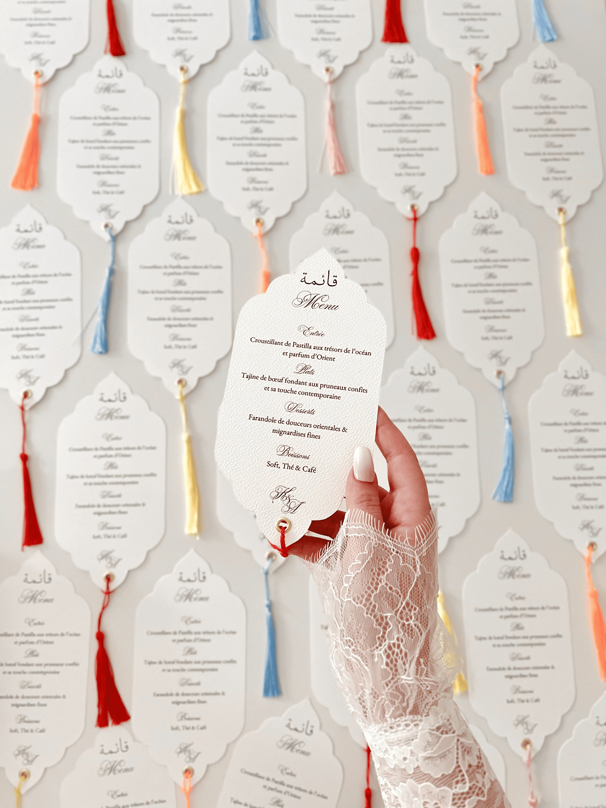 Menu de mariage personnalisé Collection ORIENT avec découpe Die Cut, calligraphie arabe bilingue, monogramme et finition avec gland coloré.