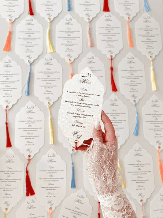 Menu de mariage personnalisé Collection ORIENT avec découpe Die Cut, calligraphie arabe bilingue, monogramme et finition avec gland coloré.